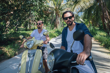 Naklejka premium Two men on motorcycles in palm trees on a tropical island