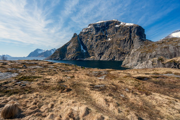Fototapeta na wymiar Panorama of picturesque landscape scenery with snow covered mountains and blue sky. Rock look like a sleeping dragon. From Aa in Lofoten, Norway.