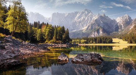 Awesome alpine highlands in sunny day. Scenic image of fairy-tale lake during sunset.  Majestic Rocky Mountains on background. Wild area. Fusine lake. Italy, Julian Alps. Best travel locations.