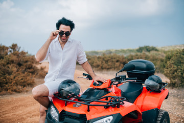 A man with a helmet in his hands next to the ATV