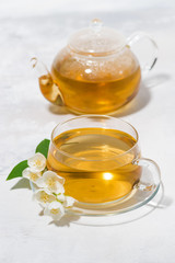 glass cup and teapot with jasmine green tea on a white background, vertical top view