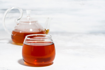 glass cup of tea and teapot on white background