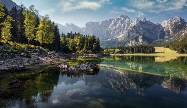 Awesome sunny landscape in the forest. Wonderful Summer scenery. Picturesque view of nature wild lake. colorful trees under sunlight. Incredible view on Fusine lakeside. Amazing natural Background