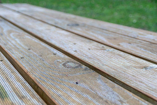 Leere Tischplatte eines Gartentisches aus naturbelassenem Holz schafft nat&uuml;rlichen Hintergrund f&uuml;r Gartenfreunde, nat&uuml;rliche Rohstoffe, nachwachsende Rohstoffe und Gartenliebe mit Camping