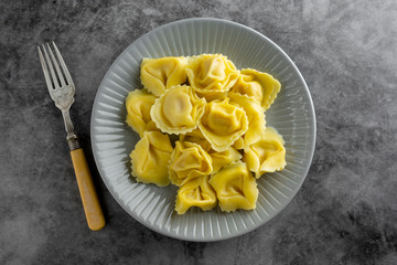 Cooked tortellini on a plate, close up pasta, italian food. Dark background.