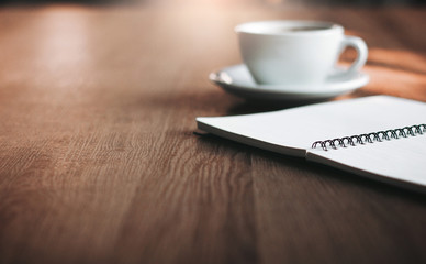 Close up of blank notebook with white cup of coffee on wooden table, Vintage style