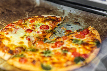 Newly baked pizza with tomato, mozzarella, onion, broccoli and cheese