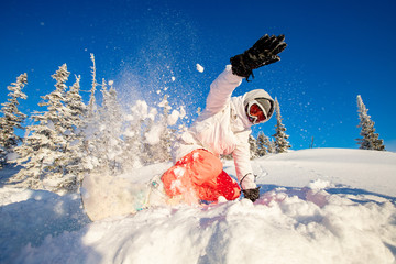 Snowboarder on snowboard rides through snow, explosion. Freeride snowboarding in Sheregesh Ski Resort