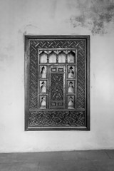 Black and white of wooden arabesque ottoman era cupboard with engraved decorations embedded in a grunge wall, Rosetta City, Egypt