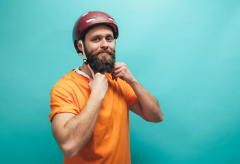 Portrait of handsome hipster guy with beard wearing blank orange t-shirt and red bike helmet ,...