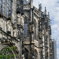 Obraz premium Detail of medieval Aachen Cathedral exterior in Aachen Germany in brown and ochre colors, featuring cathedral walls with Gothic windows, towers, sculptures and ornaments.