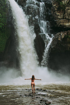 Beautiful girl having fun at the waterfalls in Bali. Concept about wanderlust traveling and wilderness culture