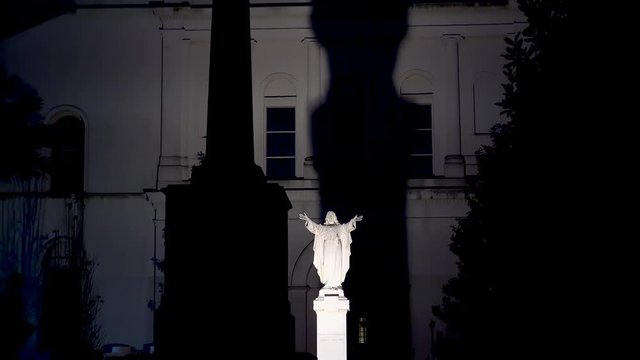 Jesus Christ statue with the huge shadow on the back side of St. Louis Cathedral by night. New Orleans, Louisiana, USA