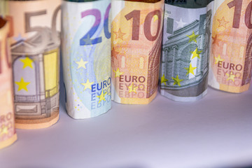 Beleuchtete und gerollte Euro-Geldscheine aus 20 euro, 50 euro, 10 euro und 5 euro Banknoten zeigen Profit, Gewinn, Ersparnisse und Dividenden im europäischen Finanzmarkt und Währungskursen