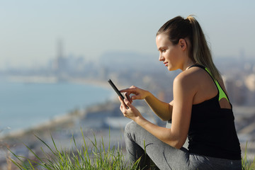 Runner checking smart phone in city outskirts after sport