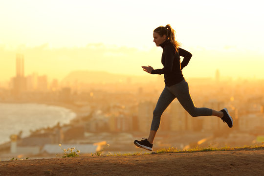 Runner running in city outskirts at sunset