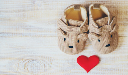 Baby booties and heart on a light background. Selective focus.