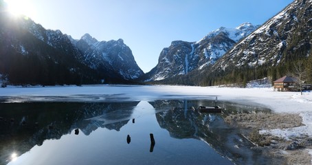 Fototapeta premium A beautiful magical view of the mountains reflected in the water in the morning sunlight. Lake Toblacher See (Dobbiaco) in South Tyrol, Dolomites, Italy