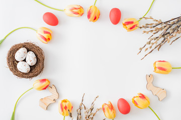 Flat lay easter composition with yellow tulips and eggs on a white background