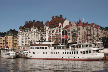 Naklejka premium Harbor view with boats and residential houses at the waterfront of the district Östermalm in Stockholm a sunny winter day