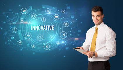 Businessman thinking in front of technology related icons and INNOVATIVE inscription, modern technology concept