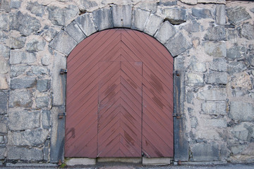 Rounded wood door in a stone wall on the island Långholmen in Stockholm