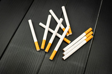 Lying cigarettes arranged on gray wooden background in a non-aligned manner