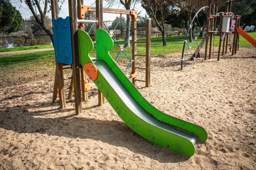 Entrance to a children's slide located in a game package with grass and trees