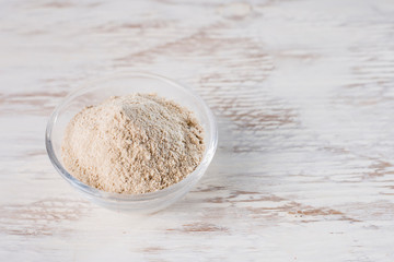Banana flour in glass bowl on wooden background