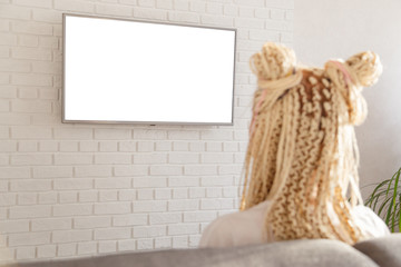 woman watching tv in living room on wall at home, white blank screen empty copy space, back view