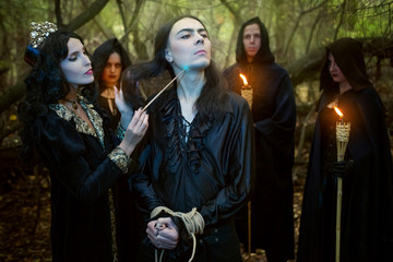 Young woman witch conduct a rite of black magic over a young man in the forest.