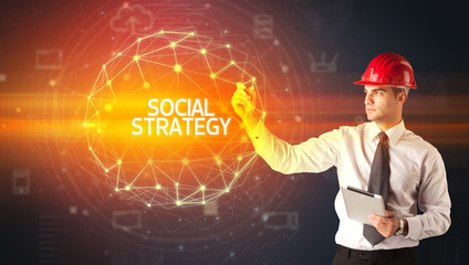 Handsome businessman with helmet drawing SOCIAL STRATEGY inscription, social construction concept
