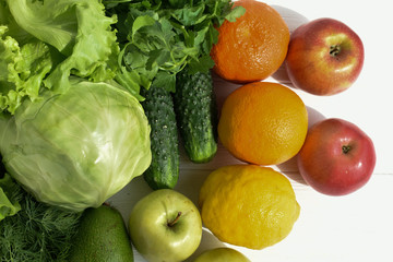 Green cabbage, parsley, cucumbers, salad, avocado, apple, orange orange, mandarin, yellow lemon, red apples on a white wooden background. Healthy eating concept. Vegetarianism.