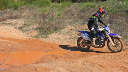 Zoom photo of mud track enduro motocross rider performing freestyle stunts in high speed