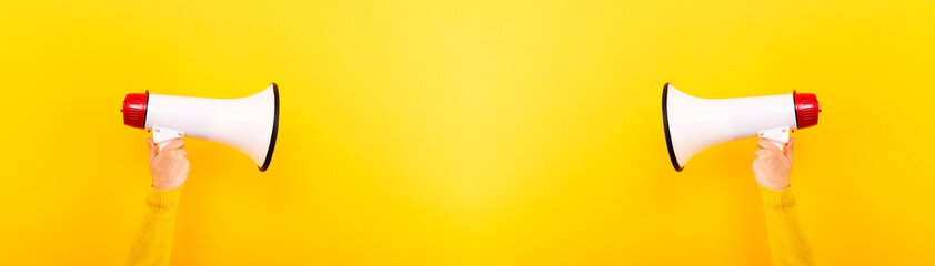megaphones in hands on a yellow background, panoramic mock-up, attention concept announcement