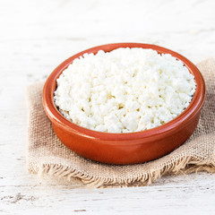 Homemade cottage cheese in a ceramic bowl on white old wooden table. Healthy food. Fresh dairy products. Close up