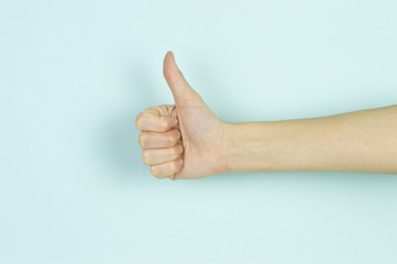 Like symbol shown by a human hand isolated on blue background.