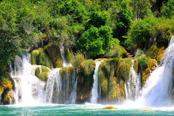 A picturesque waterfall among large stones in the Krka waterfalls, Lakes Landscape Park, Croatia in spring or summer. Croatian waterfalls, mountains and nature.