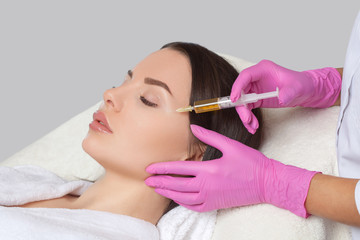 Cosmetologist does prp therapy anti wrinkle and aging skin on the face of a beautiful woman in a...