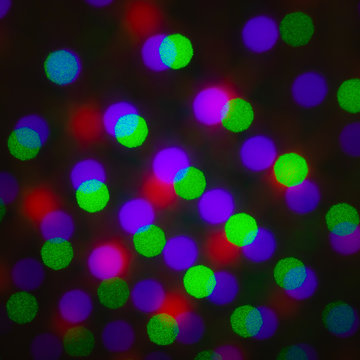 Abstract defocus background, colored green red violet purple dot circle on a black background. Illumination blurry lights, pixelated dotted abstract picture of rainbow light spots