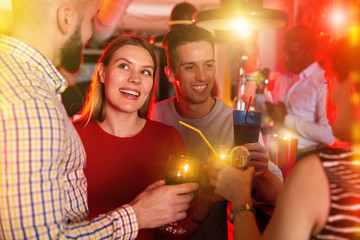 Obraz na płótnie Canvas Women and men clinking glasses at night club
