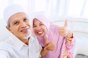 Elderly couple doing thumbs up pose in a selfie