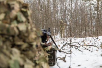An armed Soldier, in camouflage uniforms, hid a tame ambush in the woods. The fighter keeps a path...