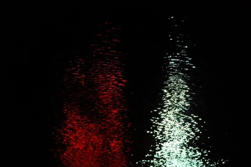 Blurred red silver light on river surface with reflection and water waves in the dark night