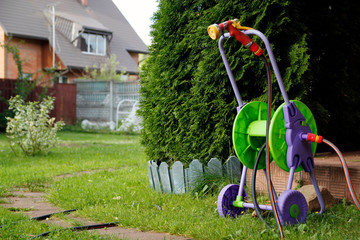 Fototapeta premium Watering hose on a trolley in garden 