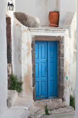 Fototapeta na wymiar Exterior of traditional greek house - background with blue door, white steps and flower pot