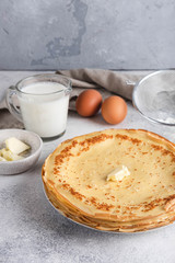 Maslenitsa week festival. A stack of russian pancakes with butter. Ingredients for cooking russian pancakes. Rustic style, close-up horisontal.