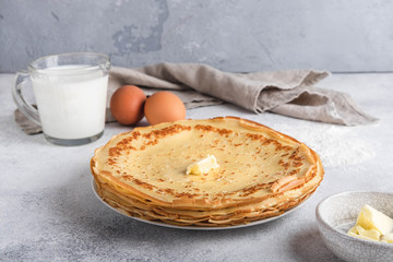 Maslenitsa week festival. A stack of russian pancakes with butter. Ingredients for cooking russian pancakes. Rustic style, close-up horisontal.