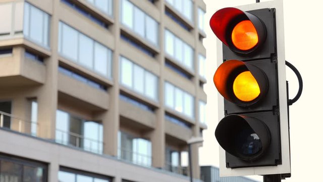 British Traffic Lights Changing From Red to Green Close Up With Green Arrow Up Close Up Against a Building in the Background