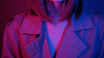 High gorgeous fashion model posing in studio.Shooting of enchanting young woman with straight hair, touching face. Close-up footage in neon lights. Style, editorial. Colourful.
